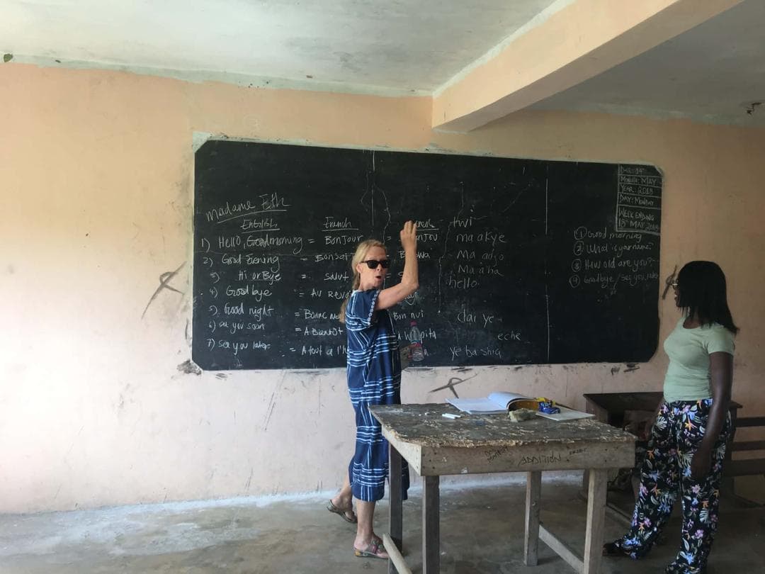 A volunteer teaches an English, French, and Twi greetings lesson